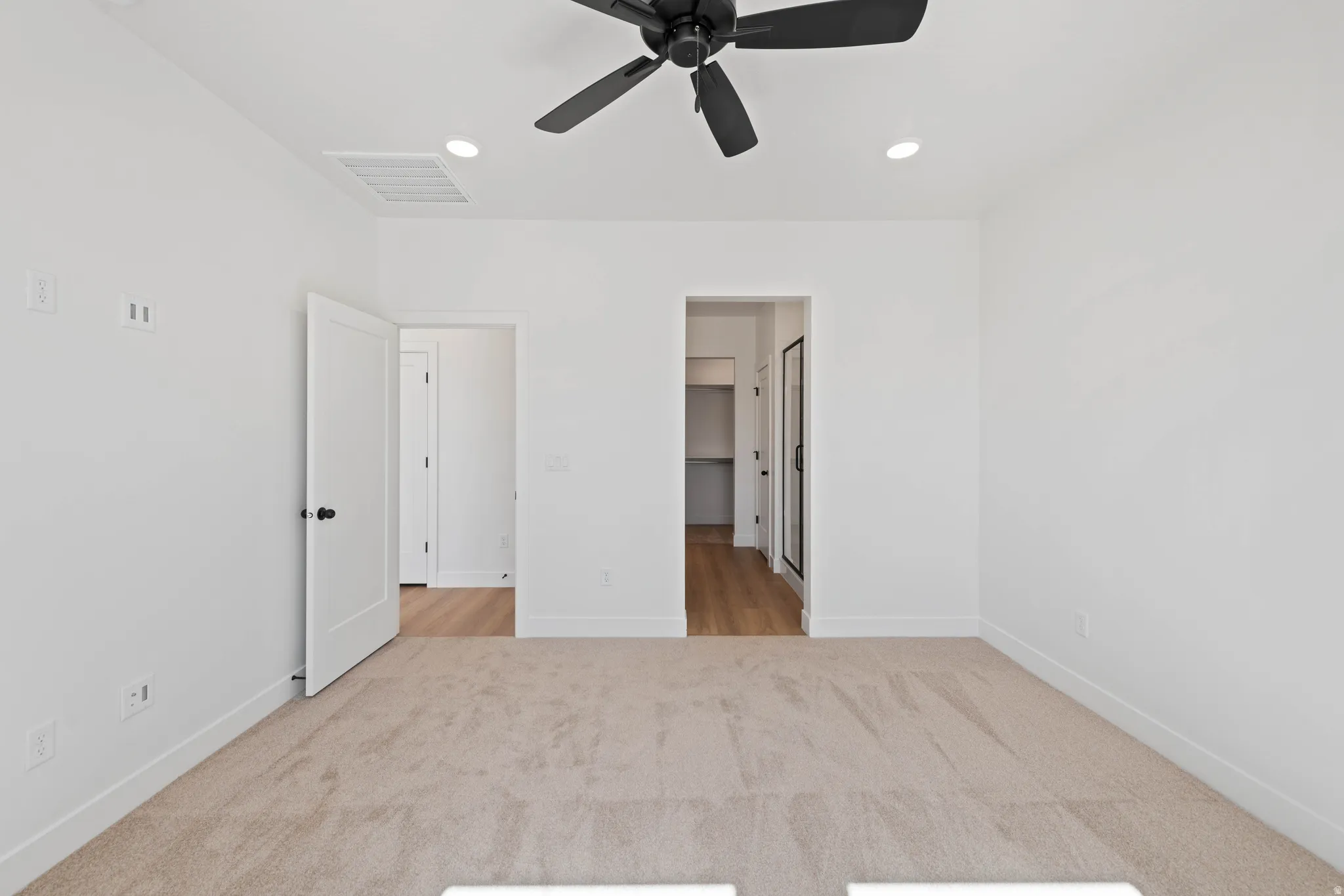 Recessed lighting, ceiling fan, and light-toned carpeting