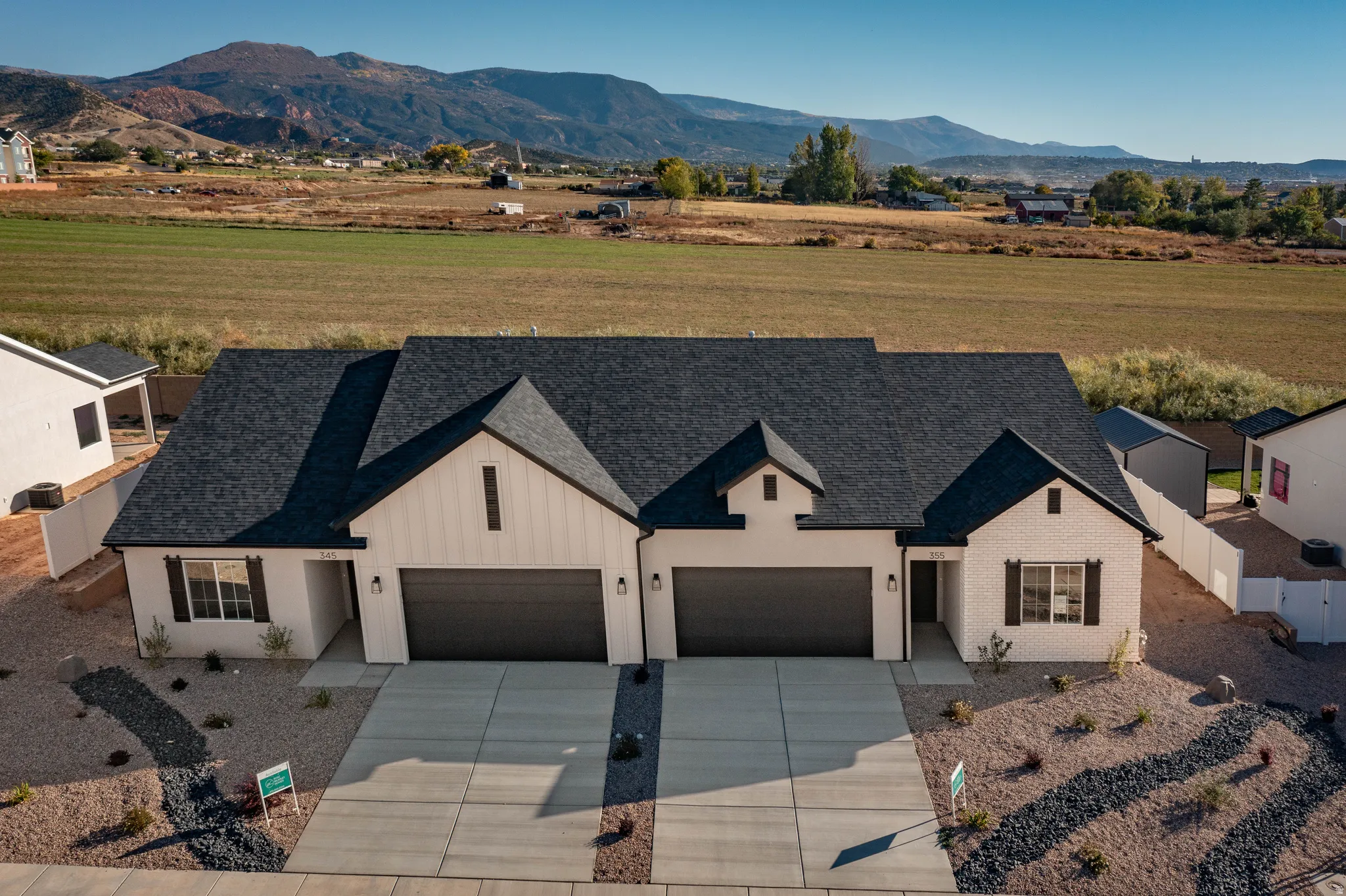 Duplex with light-colored exterior finish, dark roofing, and attached two-car garages