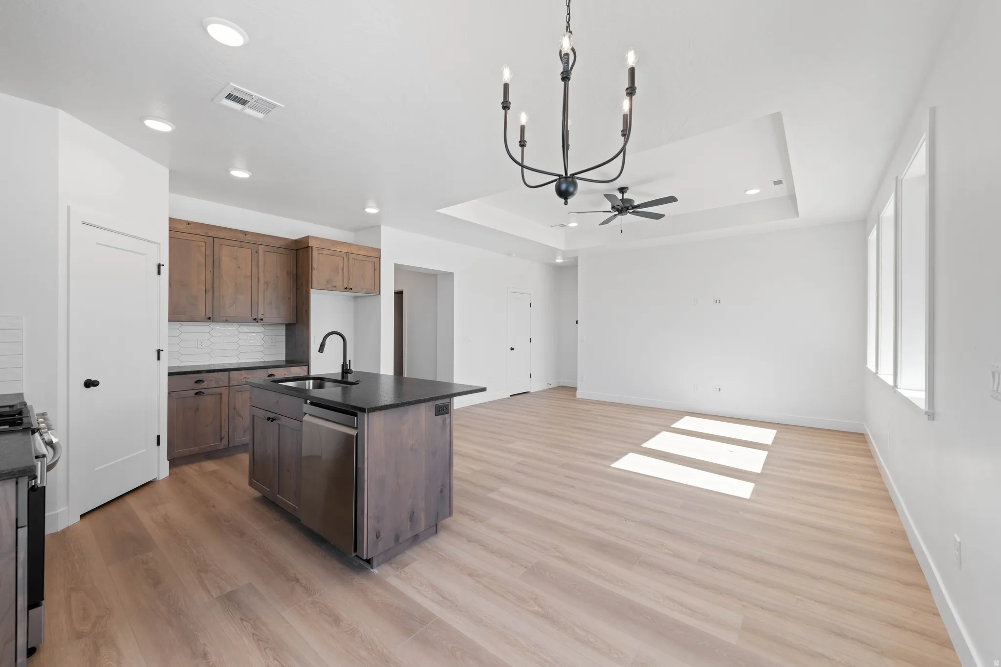 Kitchen island with dark countertop, stainless steel appliances, and dark wood-finish cabinetry