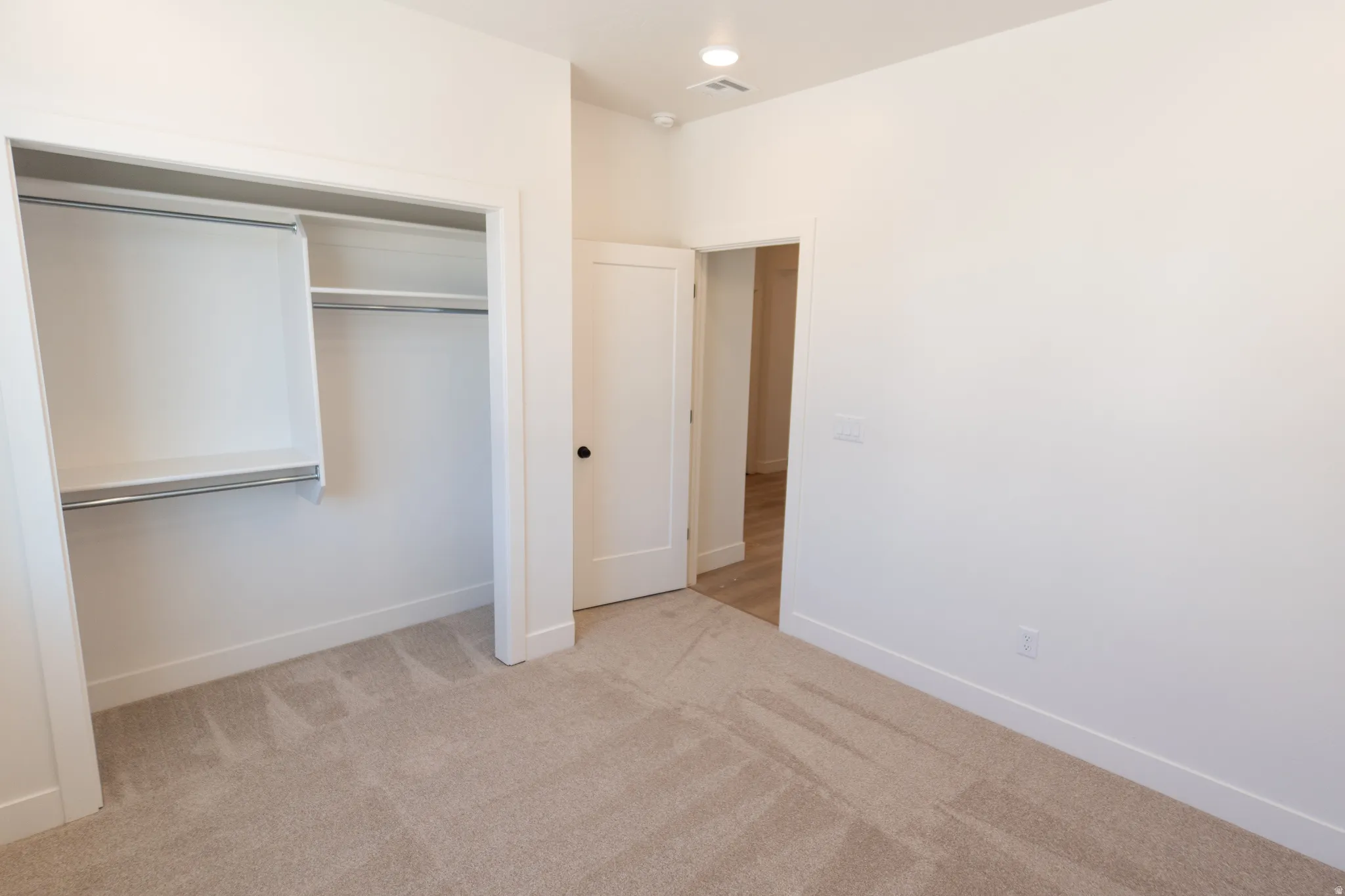 Carpeted room featuring a built-in closet with shelving and hanging rods