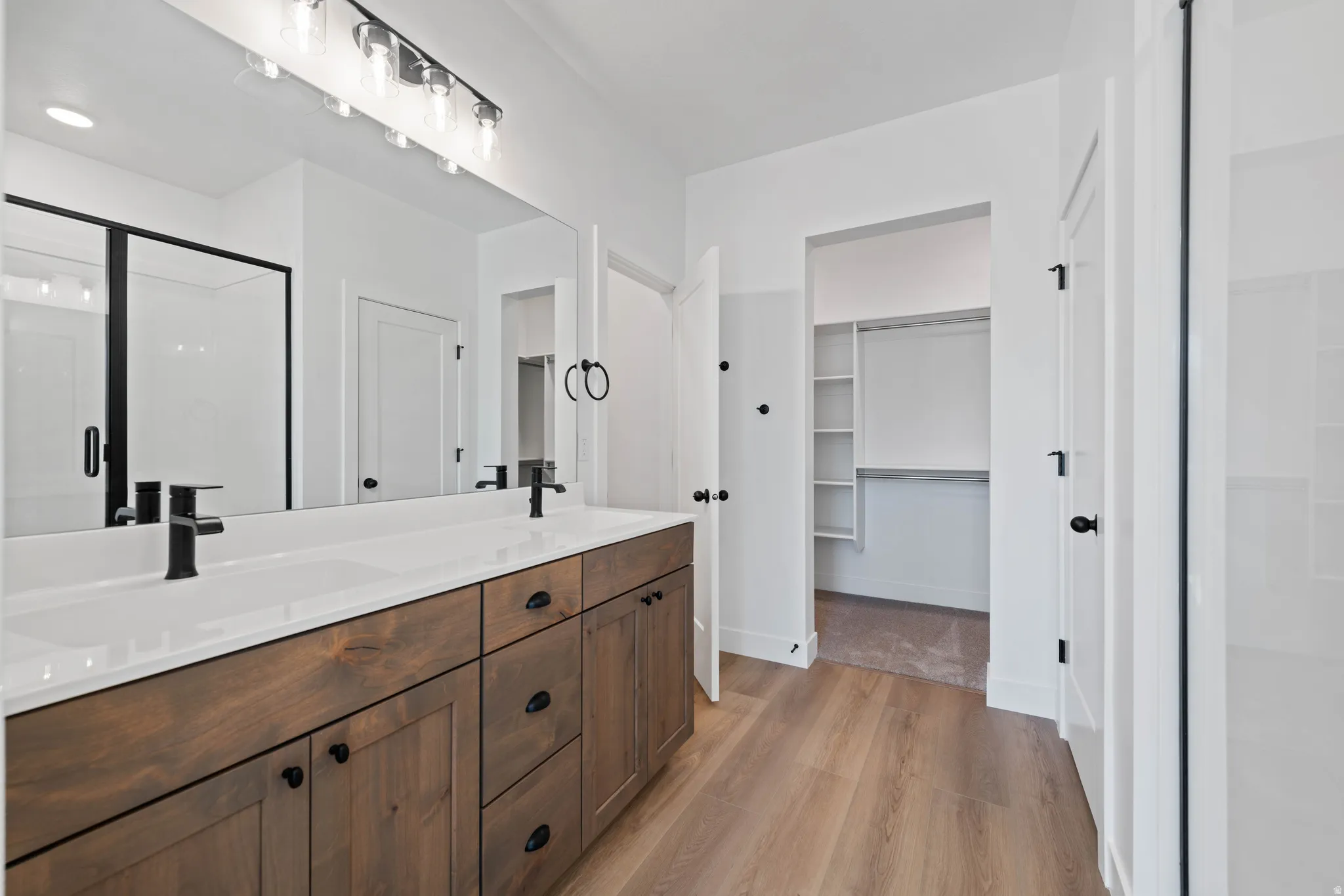 Dual vanity with dark wood-finish cabinetry, white countertop, and matte black fixtures