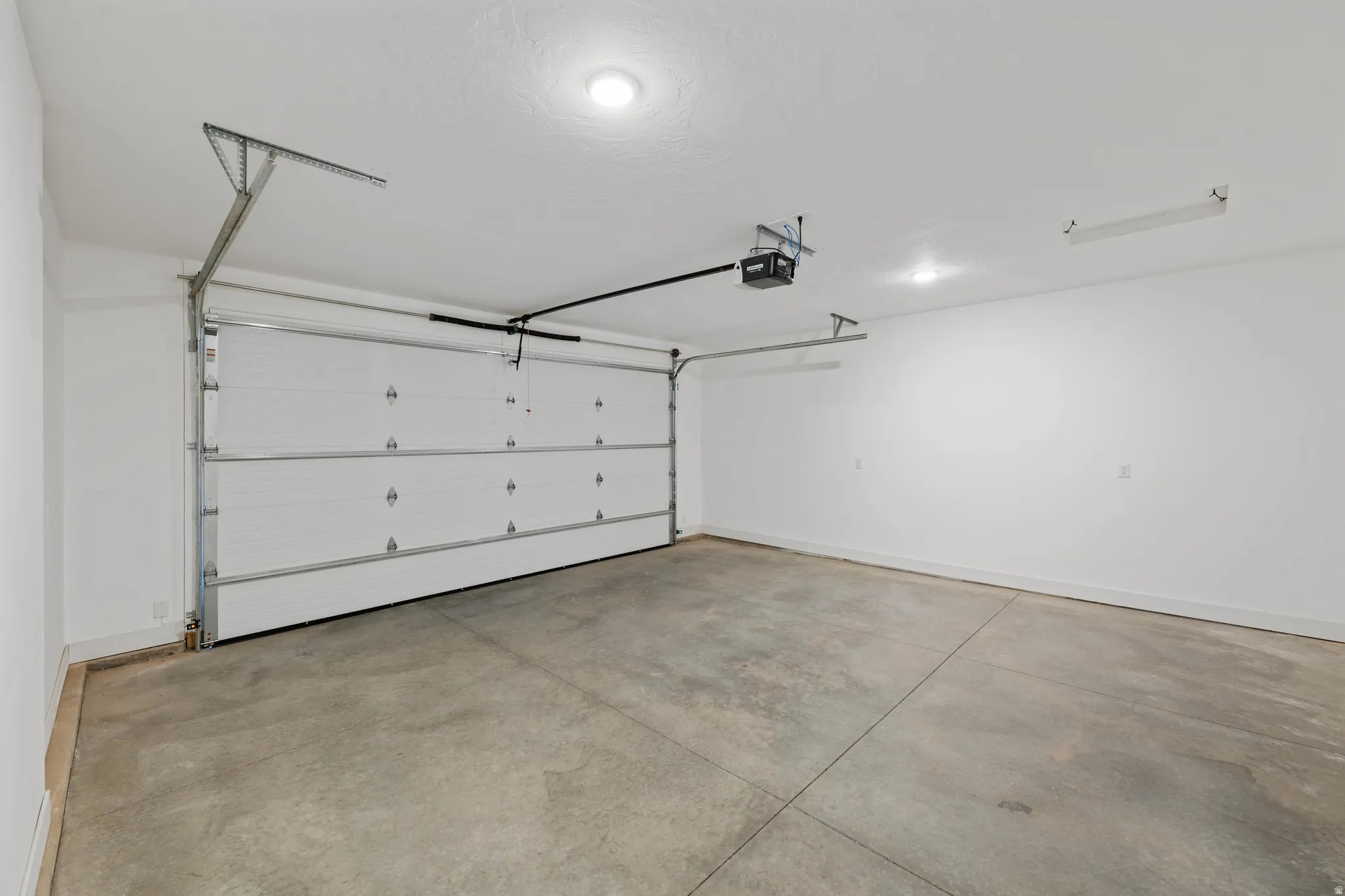 Spacious garage featuring a concrete floor, white walls, and an automatic overhead door
