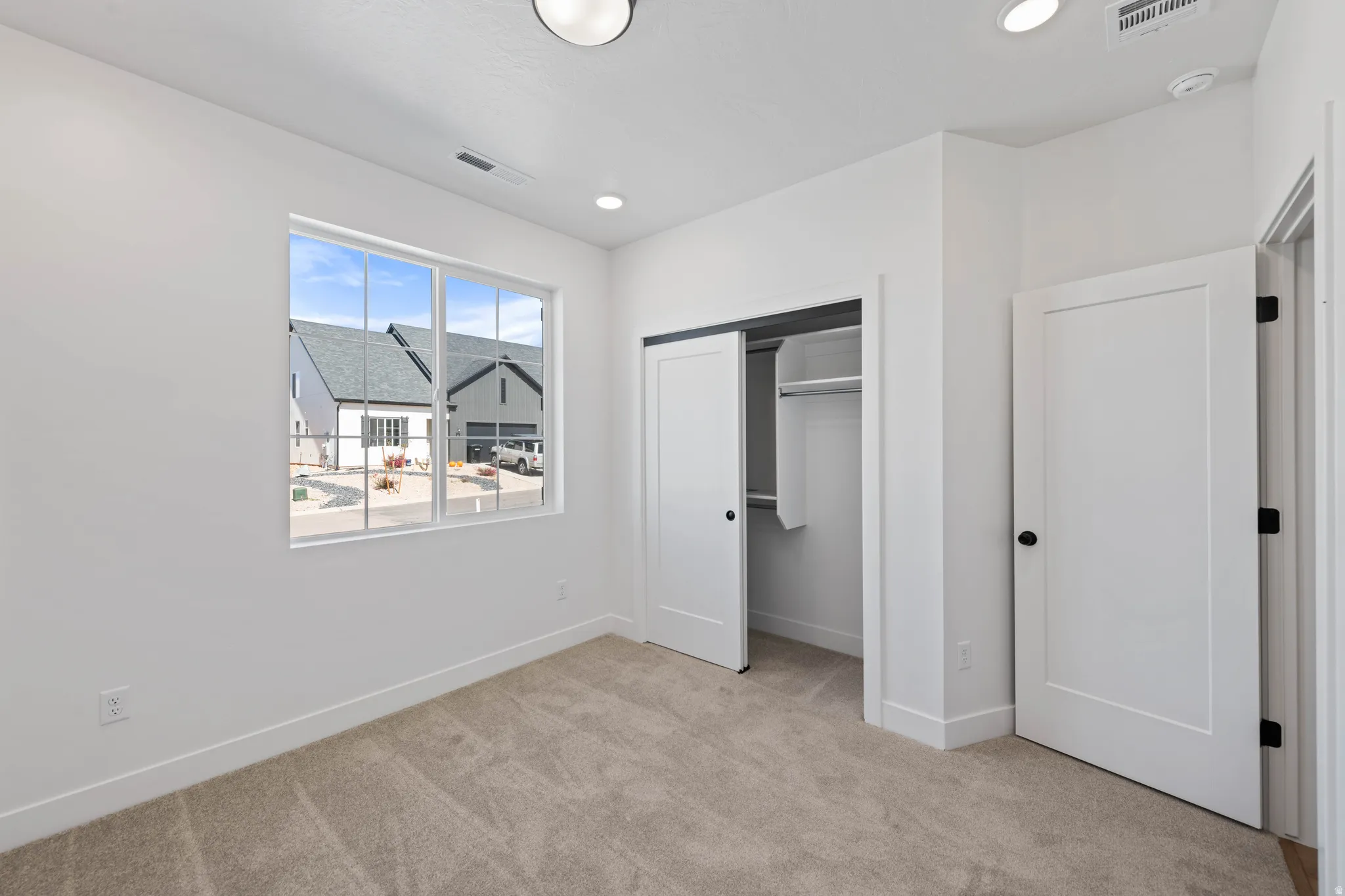 Plush carpet flooring, recessed lighting, and a window with grid patterns
