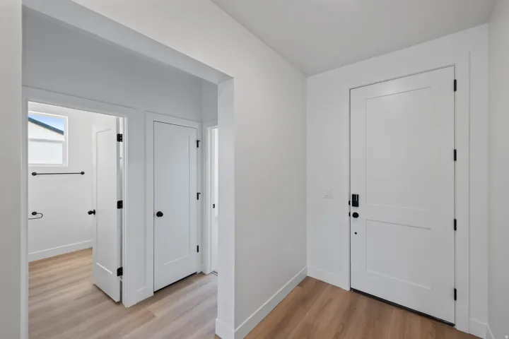 Wood-finish flooring throughout, white interior doors with matte black hardware, and crisp white walls