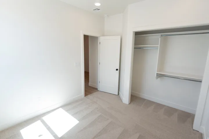Recessed ceiling lighting, white interior doors with black hardware, neutral wall tones, textured carpet flooring, and a built-in closet system