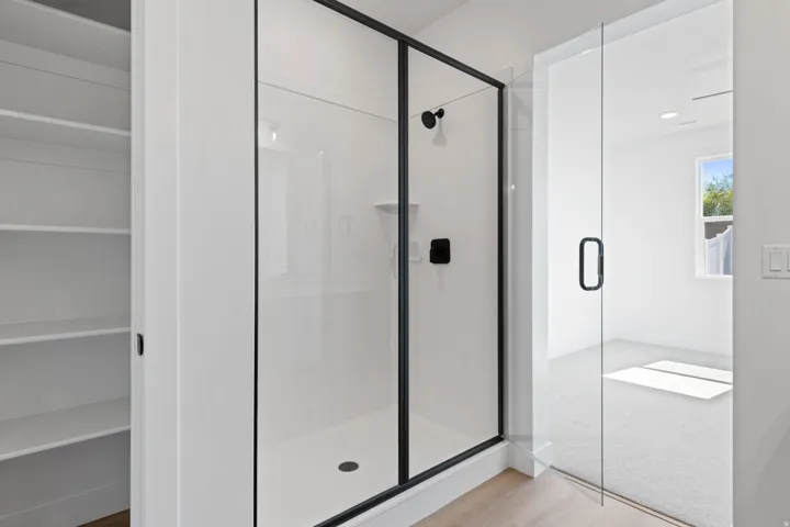Walk-in shower with black-framed glass enclosure, matte black shower fixtures, and ample built-in shelving