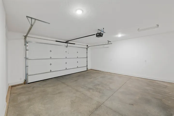 Spacious garage featuring a concrete floor, white walls, and an automatic overhead door