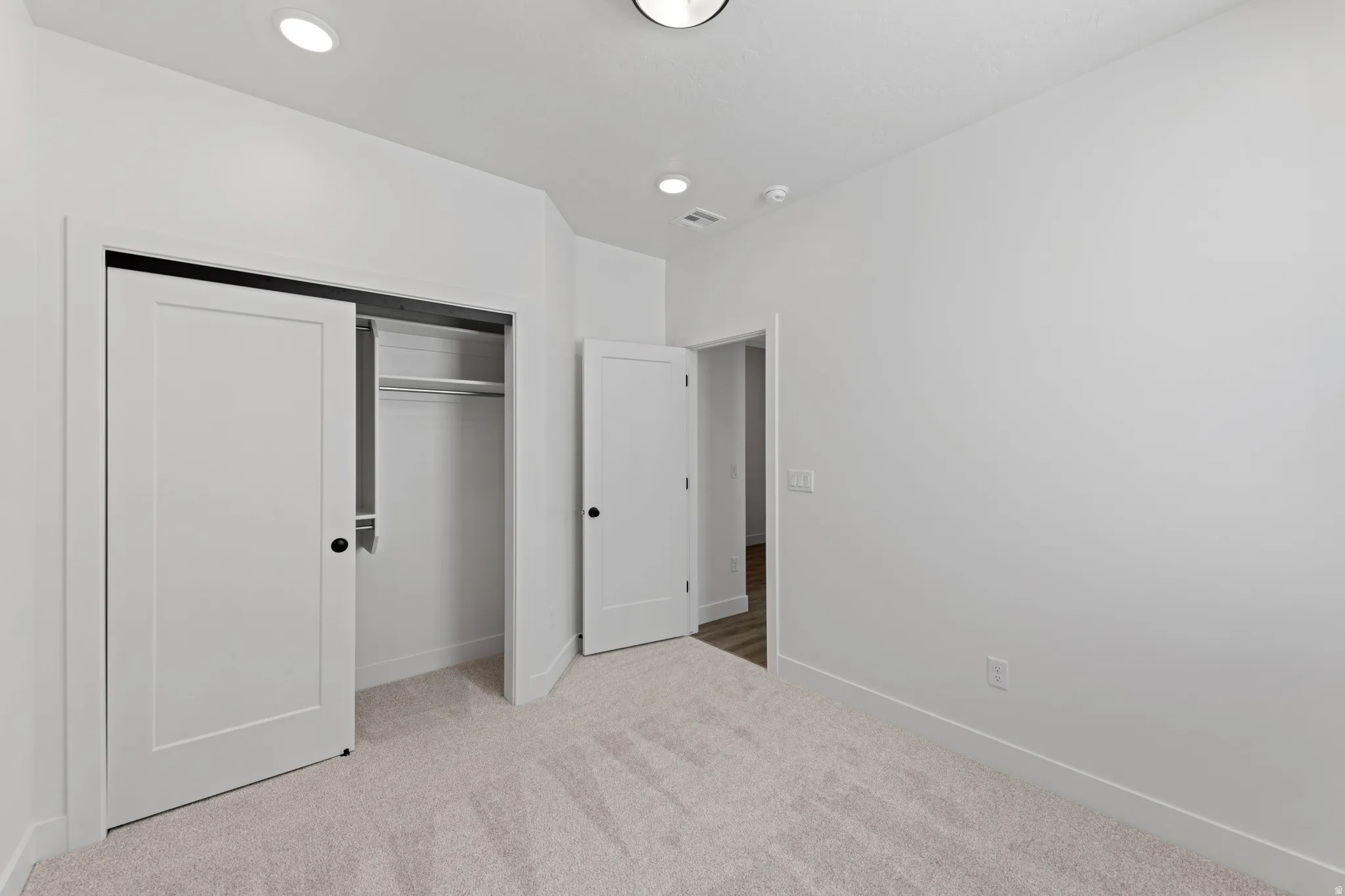 Recessed ceiling lighting, light-toned carpeting, white interior doors, and a built-in closet with shelving