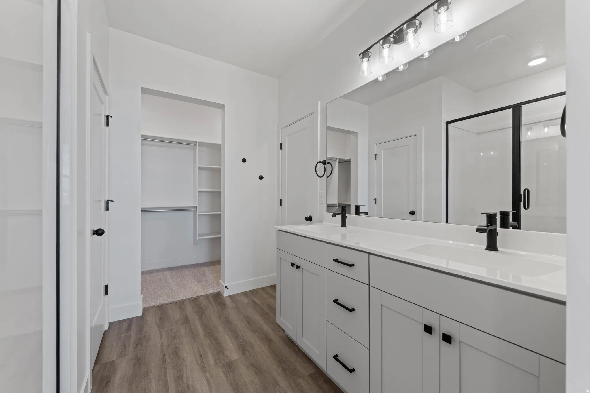 Dual vanity with integrated sinks, white cabinetry, matte black hardware, and an expansive mirror