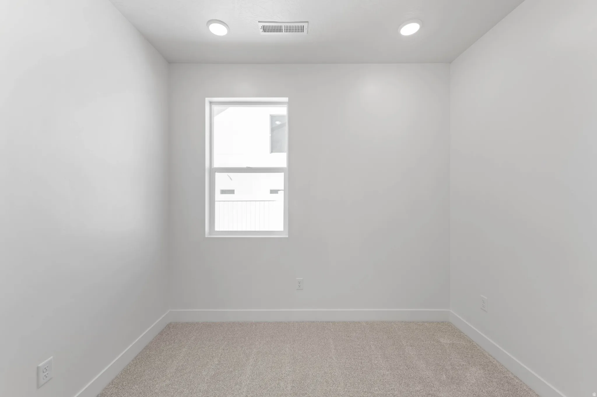 Recessed lighting, light-toned carpeting, white walls, and a single window