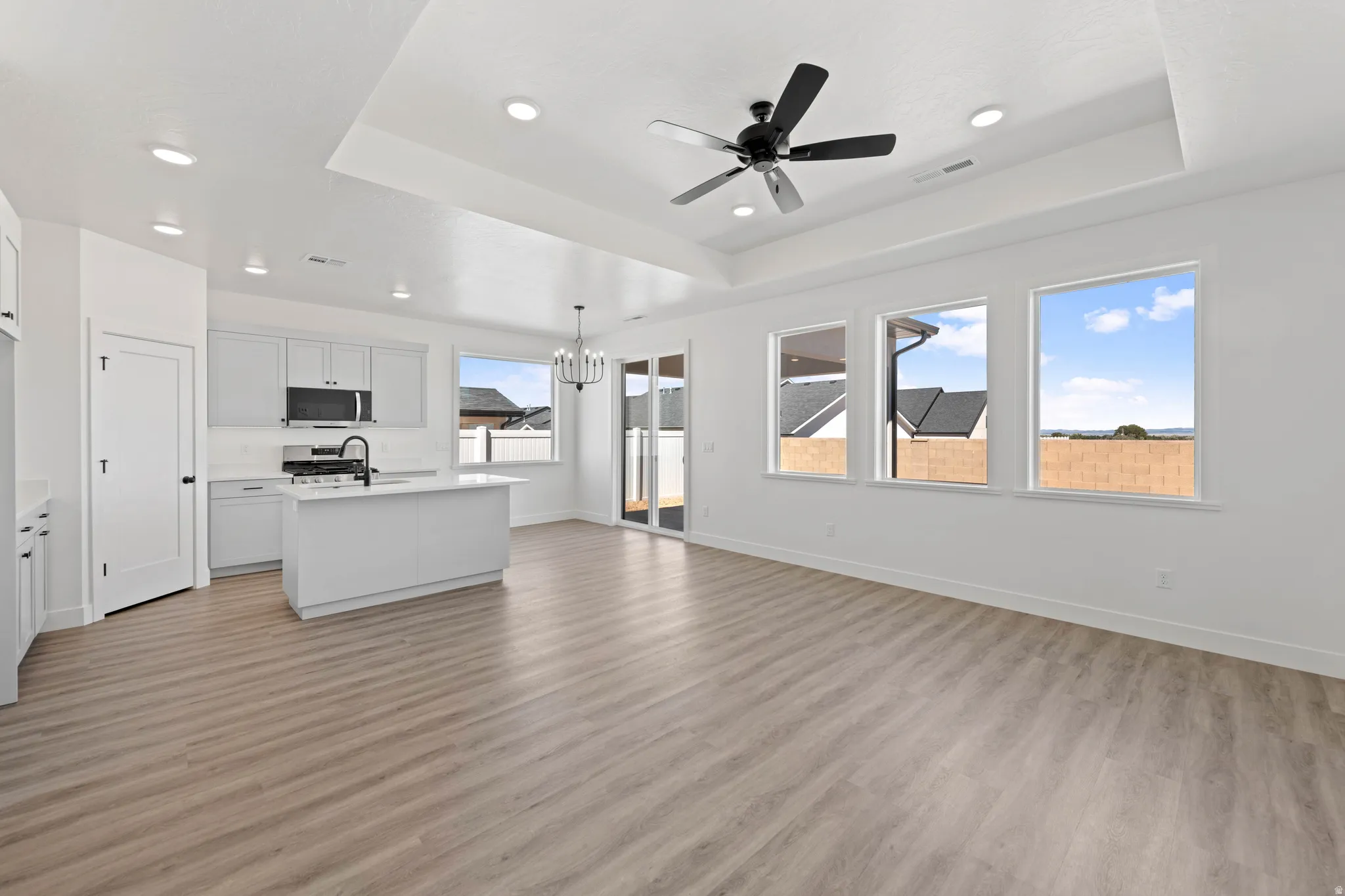 Open-concept living space featuring wood-finish flooring, a tray ceiling, and recessed lighting