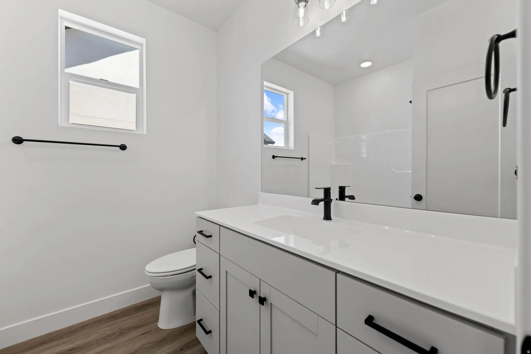 White vanity with integrated sink, matte black faucet, and cabinet hardware