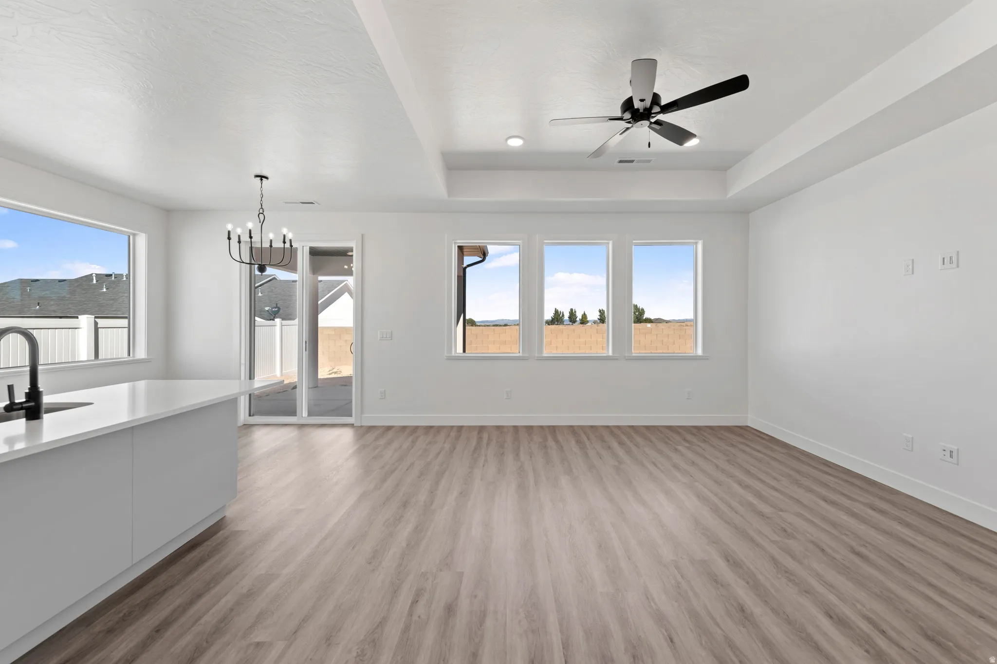 Light wood-finish flooring with white walls and a tray ceiling