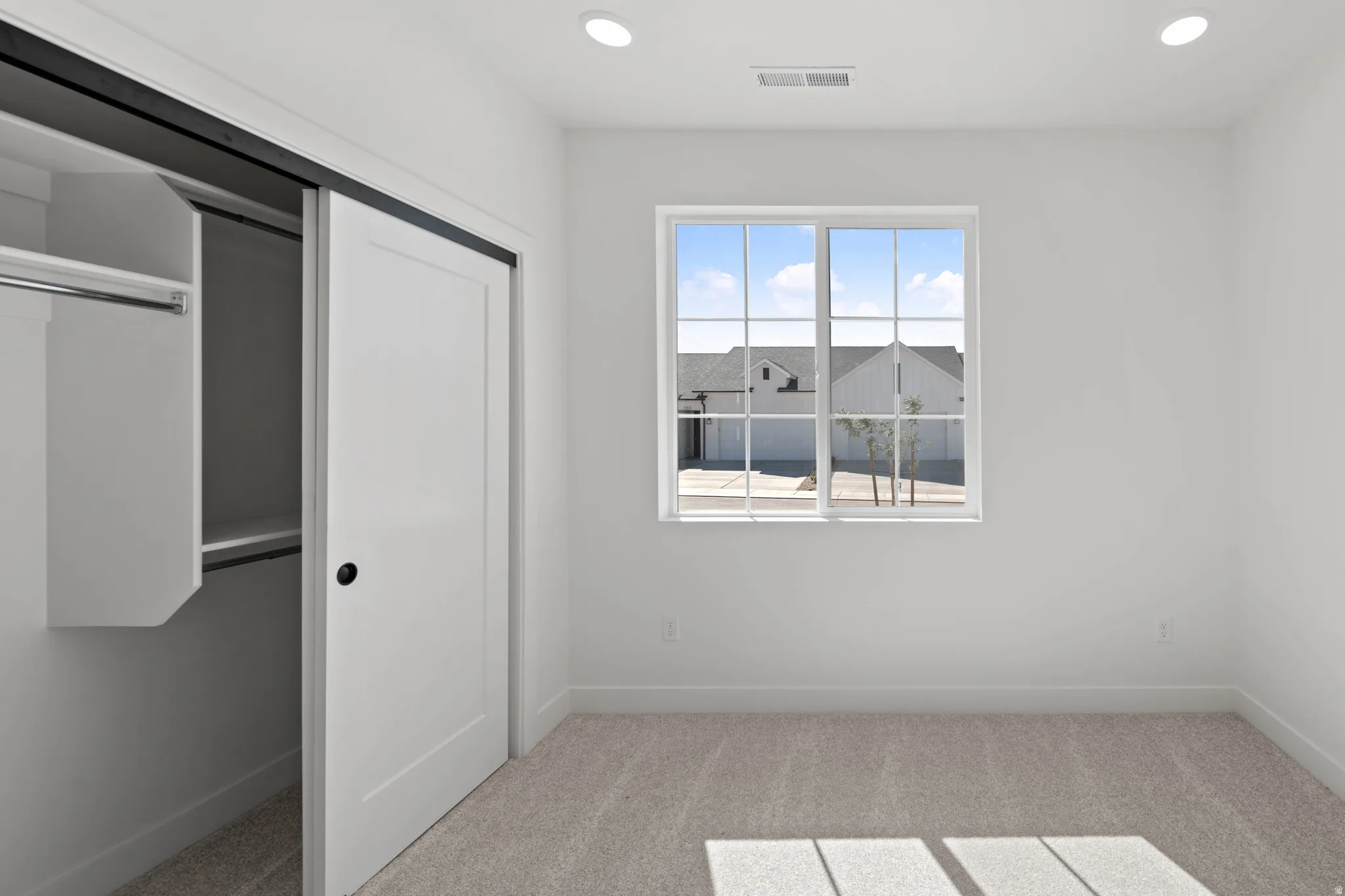 Neutral wall finishes, recessed lighting, carpet flooring, and a window with grid patterns