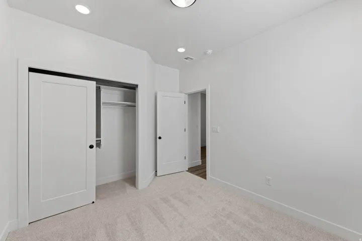 Recessed ceiling lighting, light-toned carpeting, white interior doors, and a built-in closet with shelving