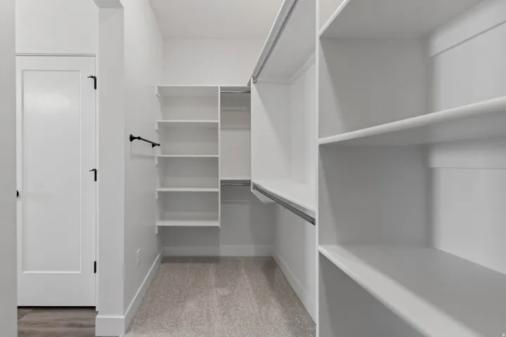 Built-in shelving, hanging rods, and neutral carpeting
