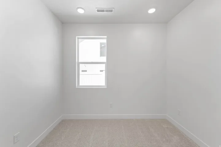 Recessed lighting, light-toned carpeting, white walls, and a single window