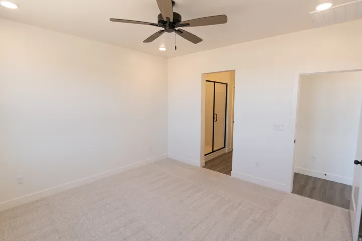 Recessed lighting, ceiling fan with wood-finish blades, light-toned carpeting, and an adjacent room with wood-finish flooring and a glass shower enclosure