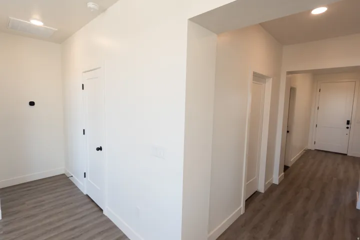 Wood-finish flooring, recessed lighting, and white interior doors with dark hardware