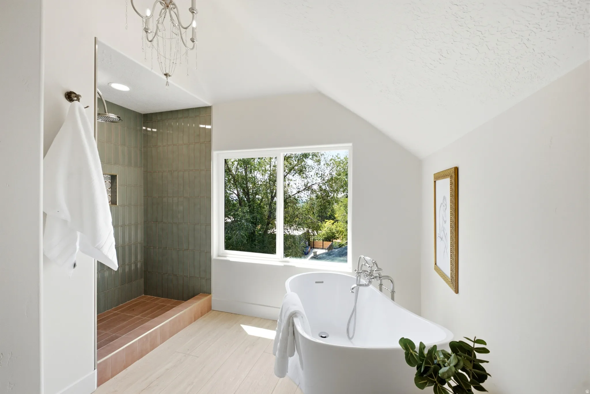 Walk-in shower with tiled walls, freestanding soaking tub, wood-finish flooring, and sloped ceiling