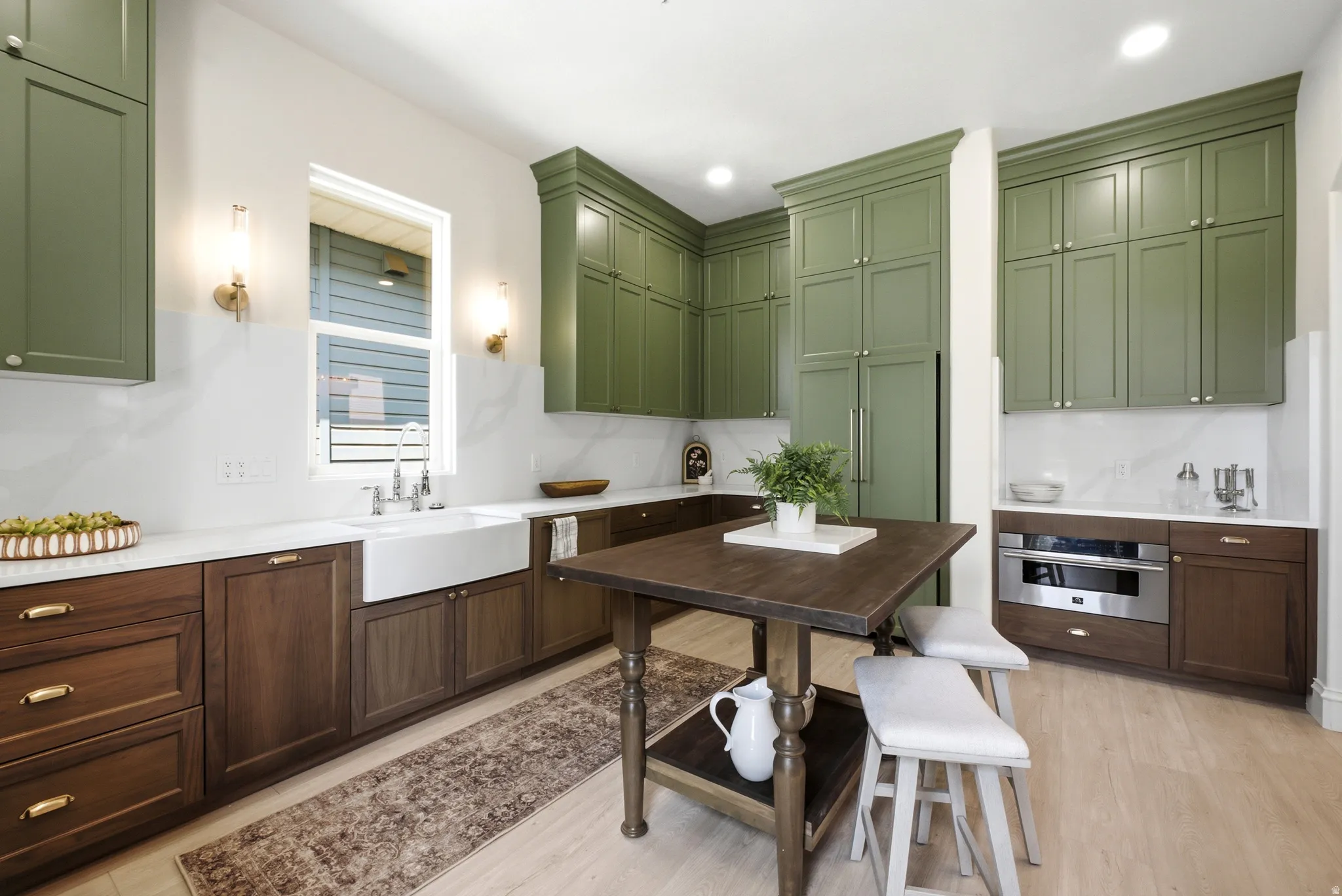 Kitchen featuring two-tone cabinetry, white countertops, an apron-front sink with a gooseneck faucet, and light wood-finish flooring