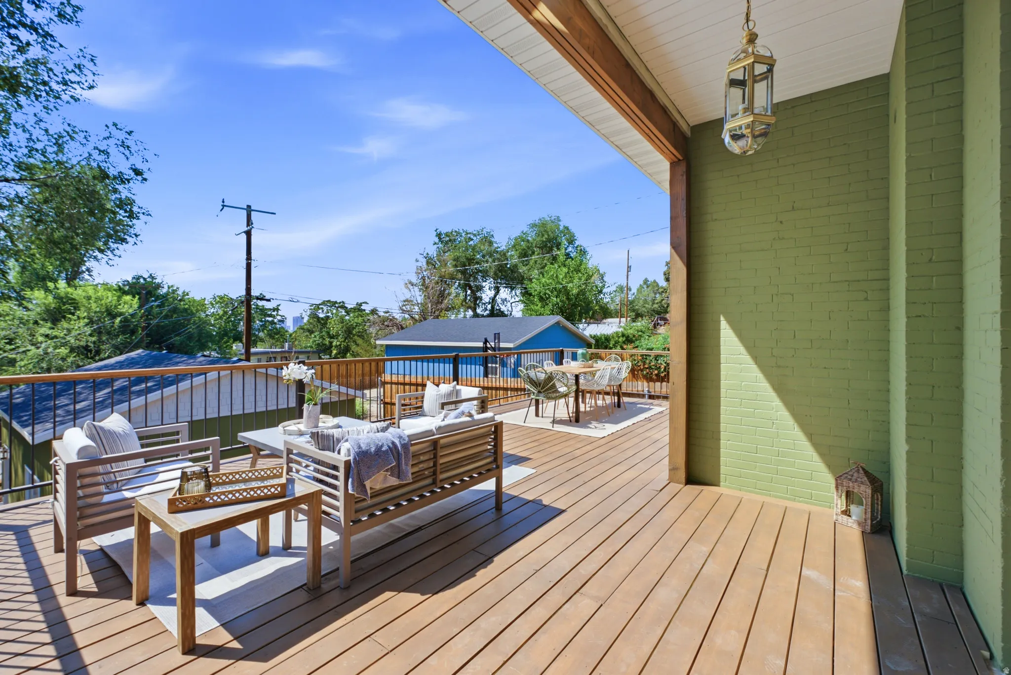Expansive outdoor deck featuring wood-finish flooring, a painted brick exterior, and a built-in outdoor lantern