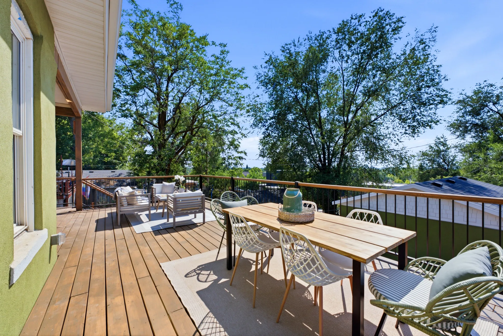 Expansive wood-finish deck with black metal railings and a painted exterior wall