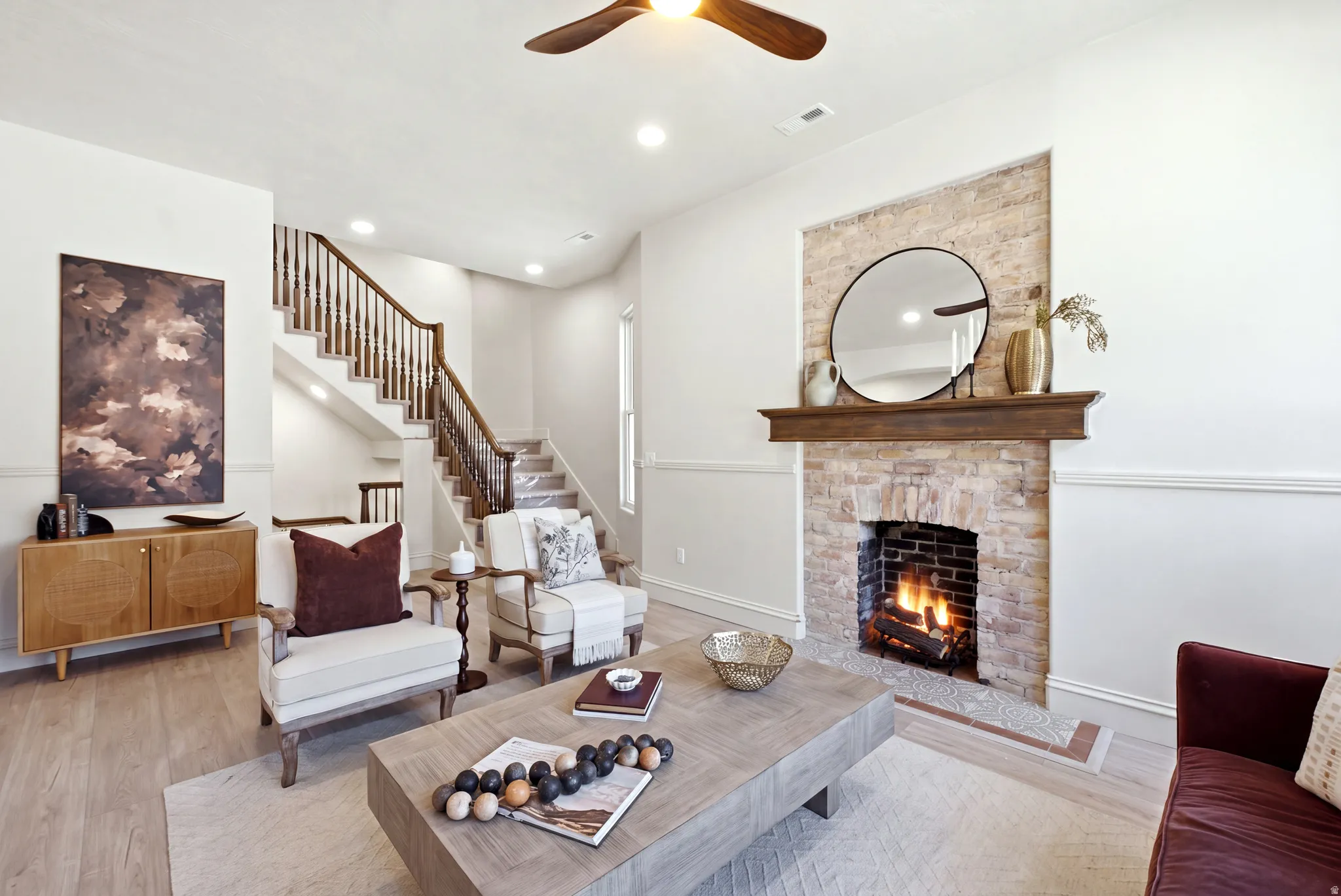Exposed brick fireplace with a wood-finish mantel, wood-finish flooring, recessed lighting, and a wood-finish ceiling fan