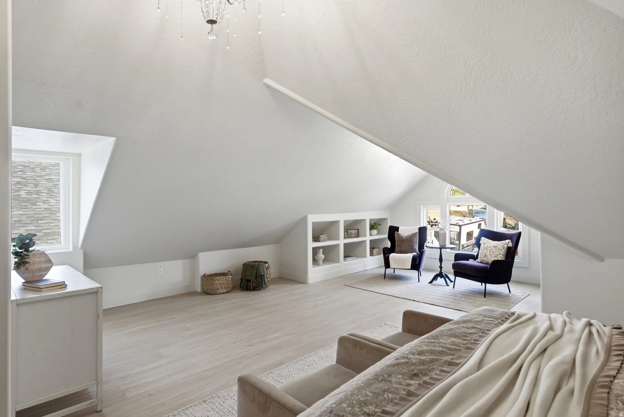 Sloped ceilings with a chandelier, wood-finish flooring, built-in shelving, and multiple windows with natural light