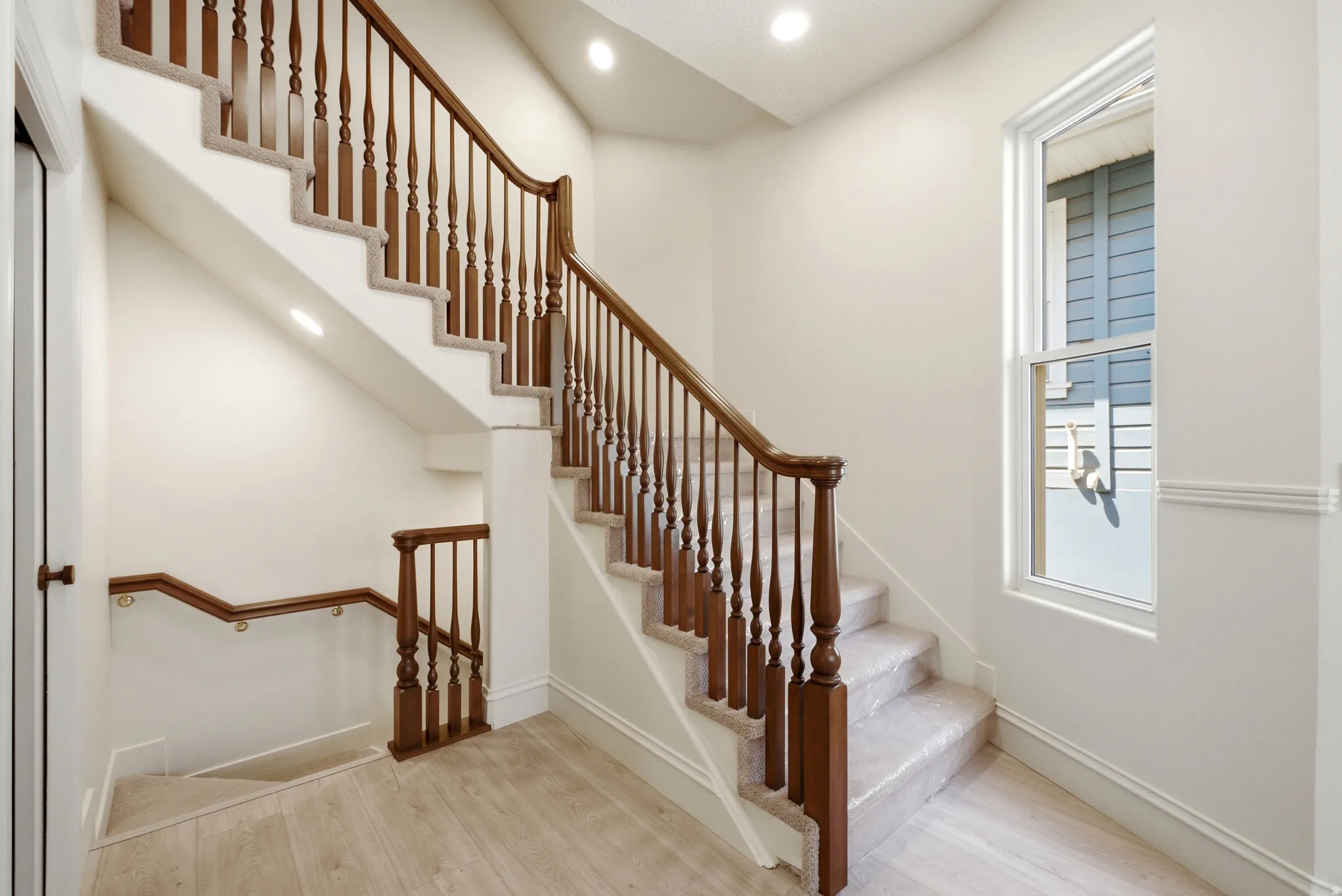 Hardwood handrails with turned wood balusters, carpeted stairs, recessed lighting, and wood-finish flooring