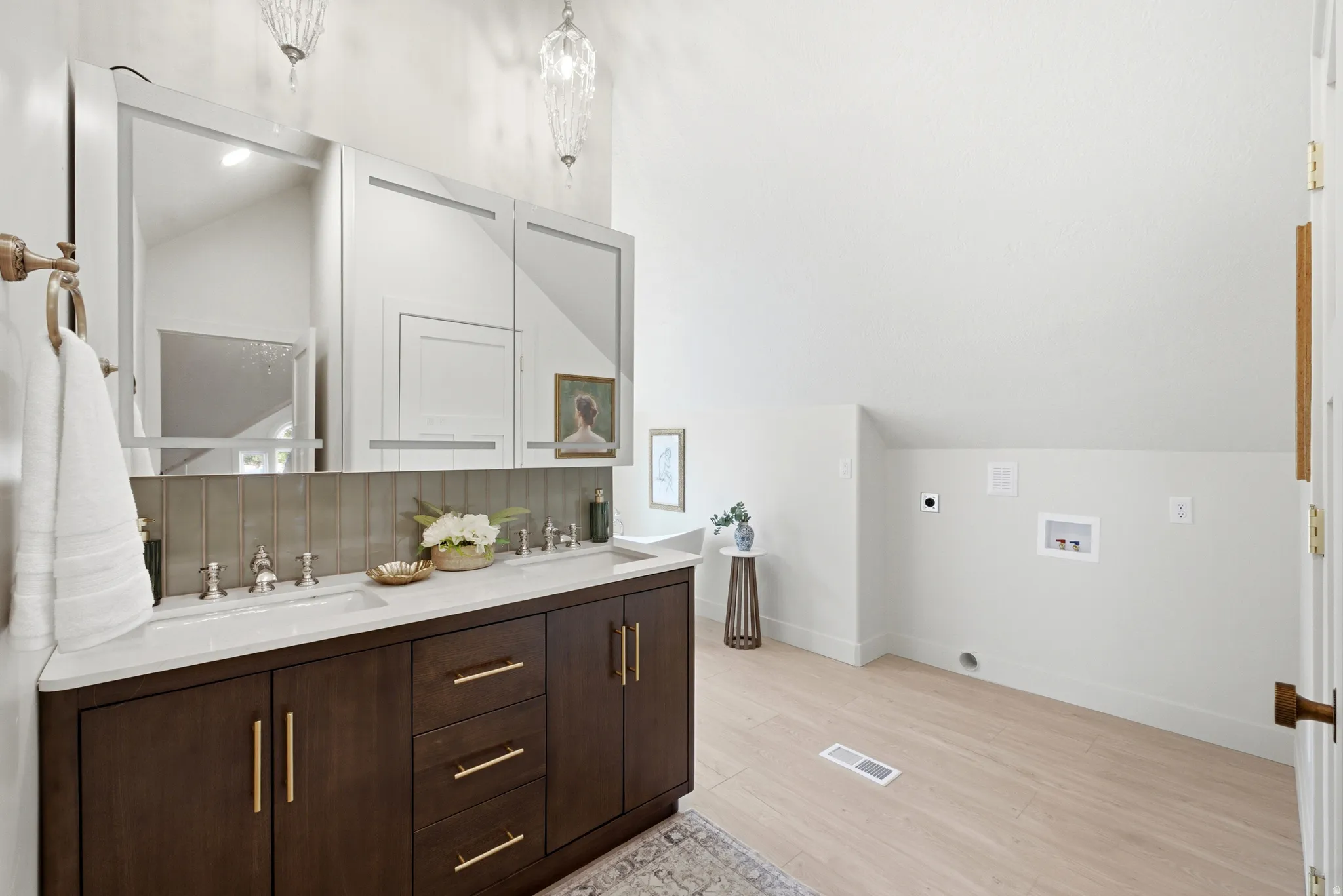 Dual sink vanity with dark wood-finish cabinetry, light countertop, and integrated sinks