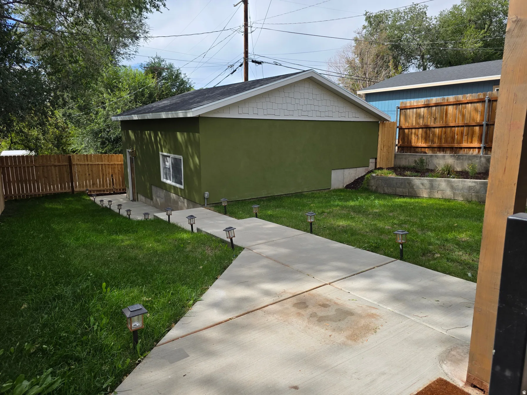 Dedicated structure with stucco exterior, concrete pathway, and landscaped retaining wall