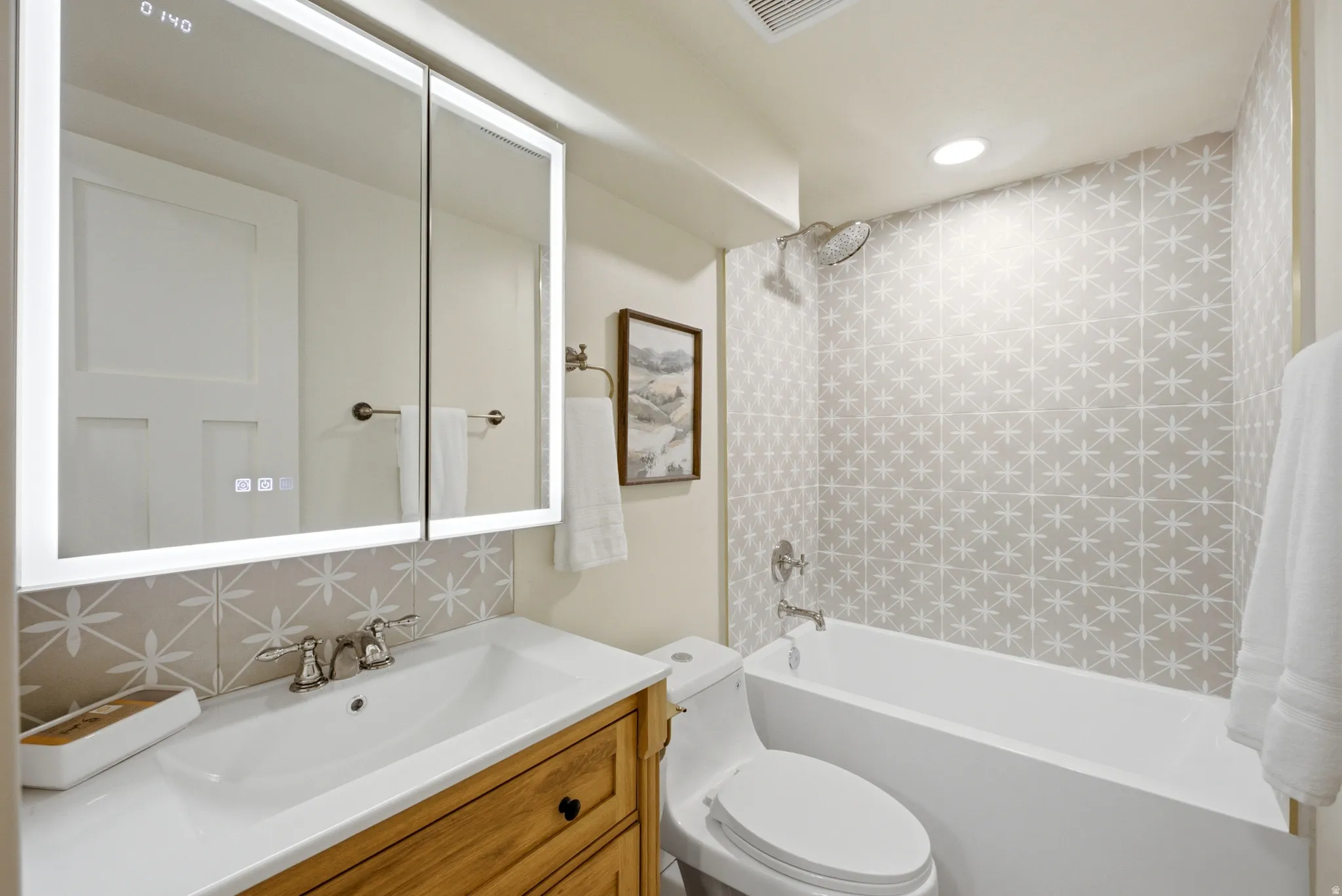 Bathroom featuring a wood-finish vanity, integrated sink, and an illuminated mirrored medicine cabinet
