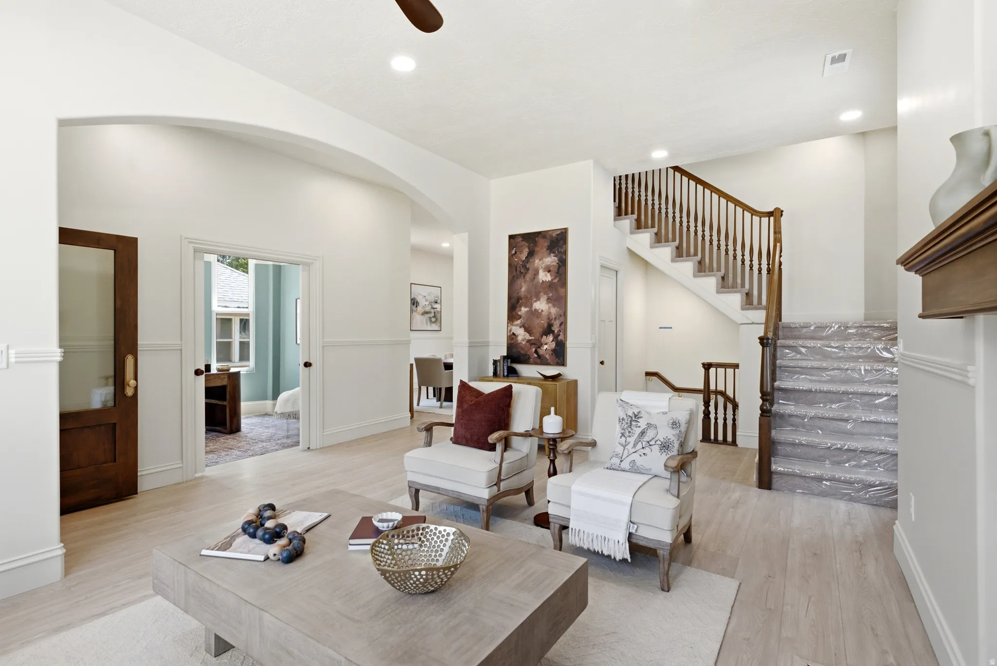 Hardwood-finish flooring, recessed lighting, arched entryway, wainscoting, and a detailed wooden staircase