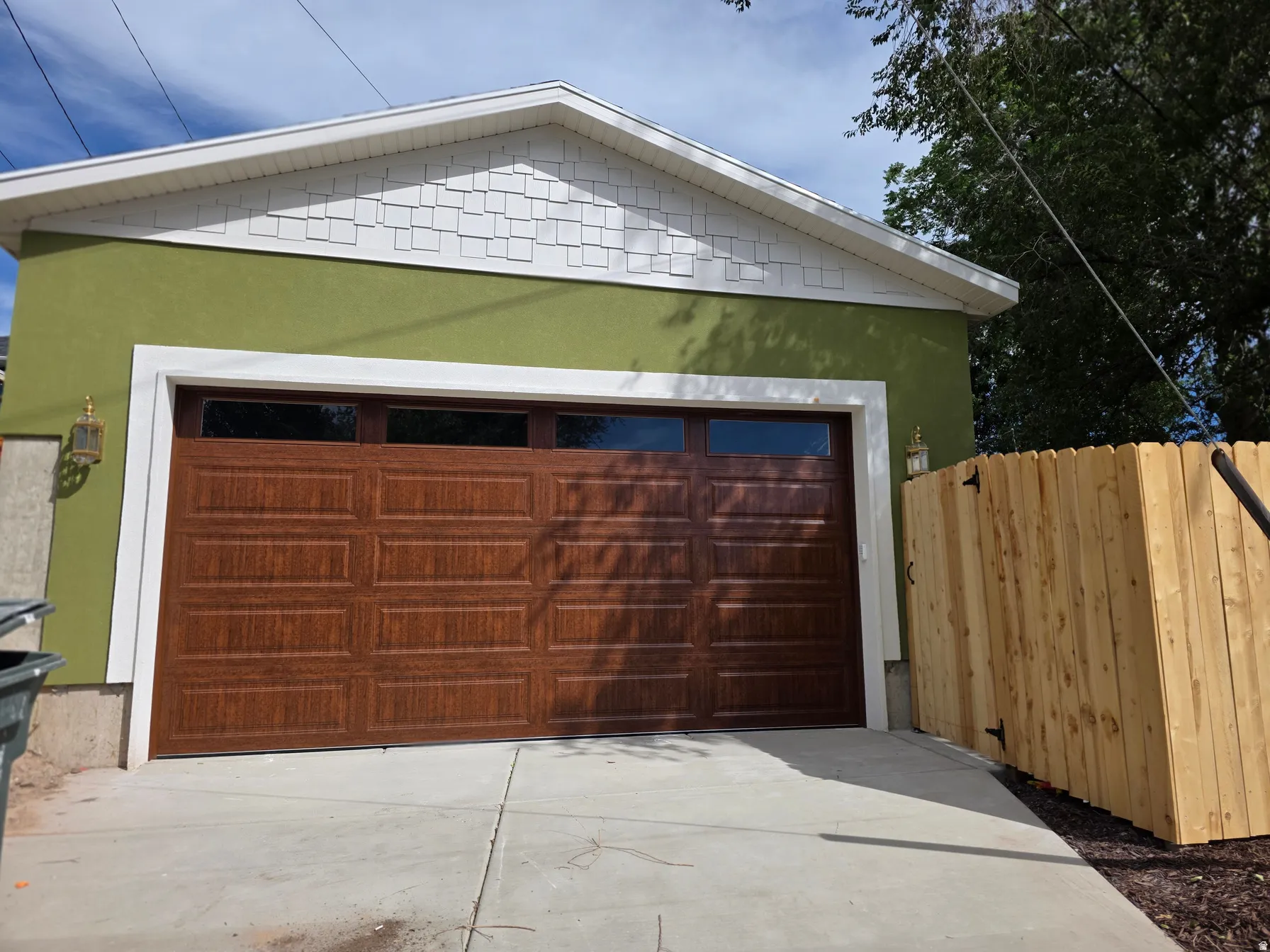 Stucco exterior in a vibrant hue, complemented by a wood-finish garage door with transom windows