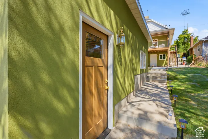 Stucco exterior with a wood-finish door and transom window, featuring an exterior wall lantern