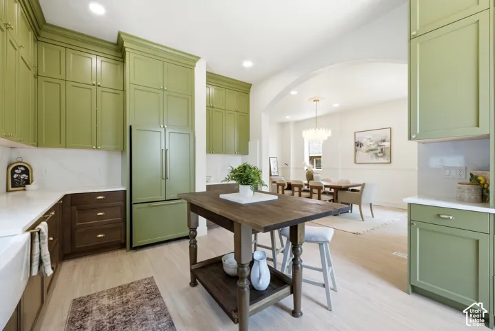 Kitchen featuring green upper cabinetry, white countertops, wood-finish flooring, and an arched entryway