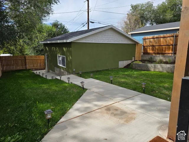 Dedicated structure with stucco exterior, concrete pathway, and landscaped retaining wall