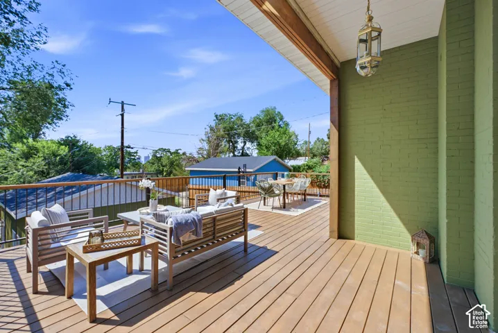 Expansive outdoor deck featuring wood-finish flooring, a painted brick exterior, and a built-in outdoor lantern