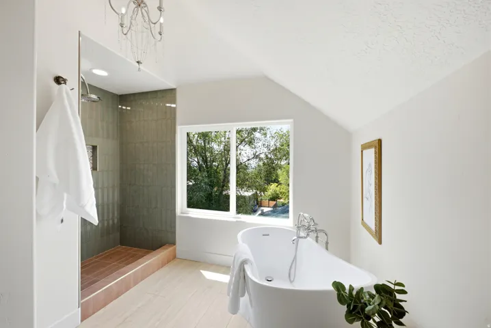 Walk-in shower with tiled walls, freestanding soaking tub, wood-finish flooring, and sloped ceiling