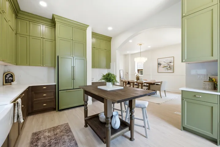 Kitchen featuring green upper cabinetry, white countertops, wood-finish flooring, and an arched entryway