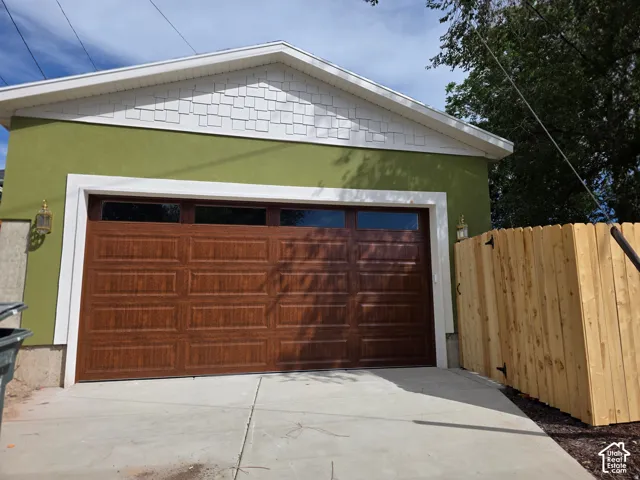 Stucco exterior in a vibrant hue, complemented by a wood-finish garage door with transom windows