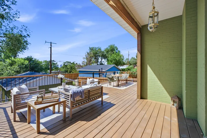 Expansive outdoor deck featuring wood-finish flooring, a painted brick exterior, and a built-in outdoor lantern