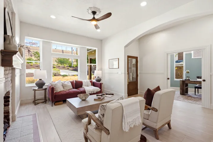 Living area featuring light wood-finish flooring, recessed lighting, a fireplace with a brick surround, and multiple windows
