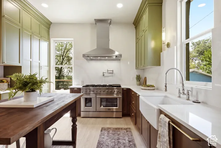 Gourmet kitchen featuring a professional-grade range with a stainless steel hood, an integrated pot filler, a farmhouse sink, and dual-tone cabinetry with extensive storage