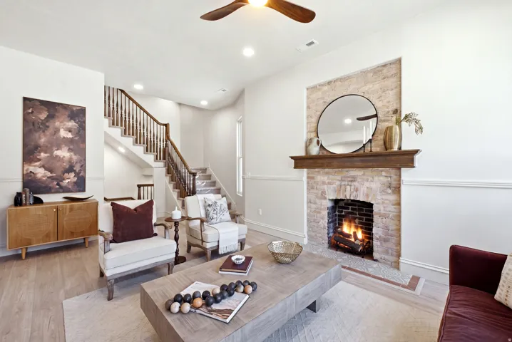 Exposed brick fireplace with a wood-finish mantel, wood-finish flooring, recessed lighting, and a wood-finish ceiling fan