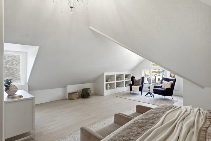 Sloped ceilings with a chandelier, wood-finish flooring, built-in shelving, and multiple windows with natural light