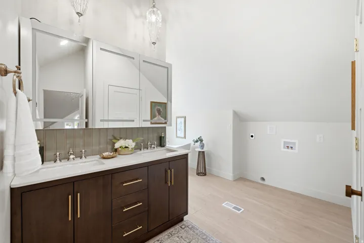 Dual sink vanity with dark wood-finish cabinetry, light countertop, and integrated sinks
