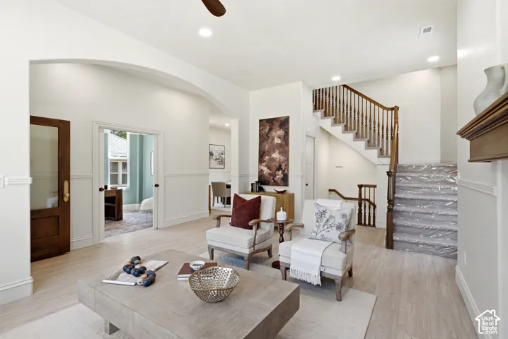 Hardwood-finish flooring, recessed lighting, arched entryway, wainscoting, and a detailed wooden staircase