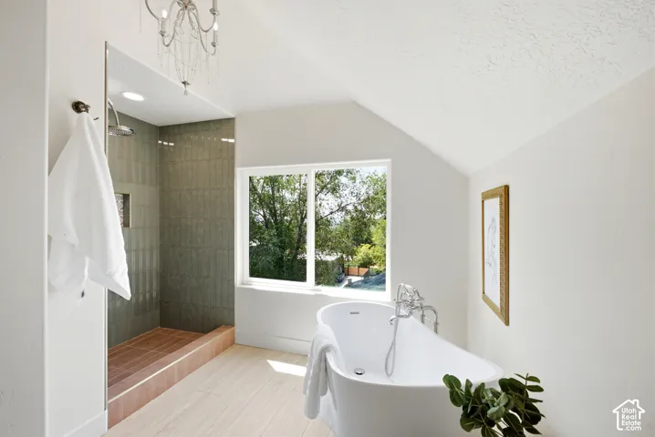Walk-in shower with tiled walls, freestanding soaking tub, wood-finish flooring, and sloped ceiling
